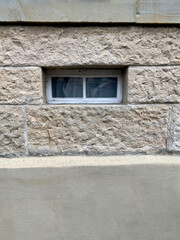 Fototapeta na wymiar Schmales Fenster in grober Sandbausteinaußenwand