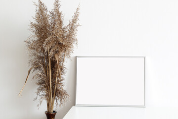 empty frame for picture with vase of dry grass