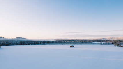 Aerial view from drone of frozen lake covered with ice and snow in winter, bird’s eye view of cold wilderness destination with beautiful scenery nature