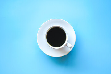 Flat lay of hot americano coffee in white coffee cup on blue background, Minimal style concept. 