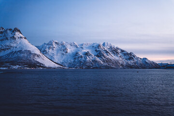 Fototapeta na wymiar Snowy mountains near water in winter