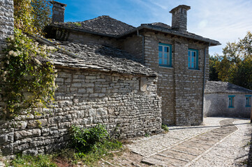 Fototapeta na wymiar Stone houses of traditional architecture and cobble-stone narrow street in the village of Papigo in Epirus, Greece