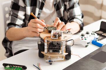 Teen hands programming and building science robotics project on his laptop at home during covid-19...