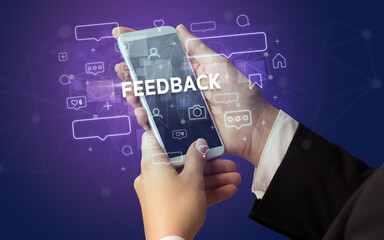 Obraz premium Female hand typing on smartphone with FEEDBACK inscription, social media concept