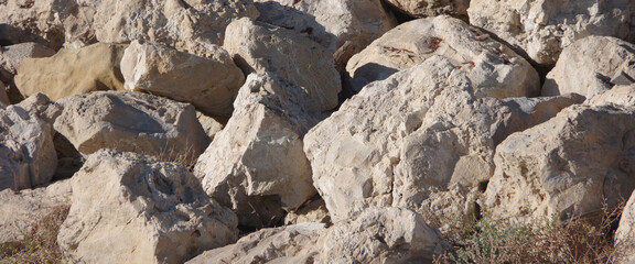 Close-up full frame view of big protective rocks and boulders behind an ocean beach