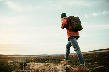 Caucasian male athlete geared up hiking on mountain during sunrise 