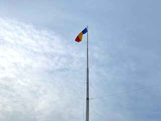 Naklejka premium The National flag of Romania winding on a blue sky background