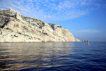 Fototapeta na wymiar Cliff with diagonal fracture lines, in the blue Mediterranean sea and under the cloudy sky, Parc National des Calanques, Marseille, France