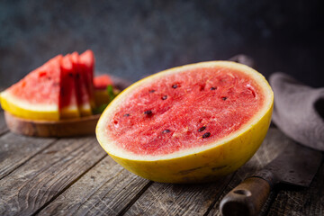 watermelon with yellow peel and watermelon slices in a wooden background.