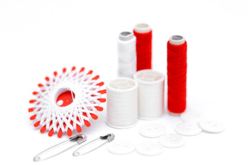 Sewing supplies on a white wooden table: sewing thread, scissors, a large spool of thread, pieces...