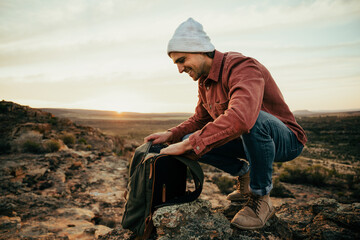 Caucasian male hiker walking through wilderness unpacking rucksack searching for water 