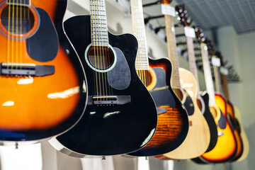 Obraz na płótnie Canvas Acoustic guitars of different colors and types on a musical instrument store window. Foreground. Selective focus