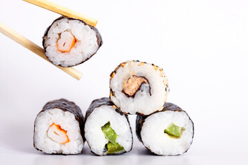Eating Sushi with chopsticks. Sushi roll japanese food in restaurant isolated on white background. Fresh hosomaki pieces with rice and nori. Closeup of delicious japanese food with sushi roll.