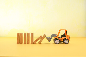 A toy bulldozer arranging the wooden blocks 