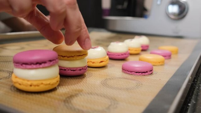The pastry chef assembles colored macarons with cream, the most delicious dessert.