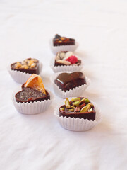 Delicious homemade chocolate with nuts and berries on a white tablecloth. chocolate candies close up