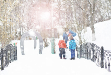 Children in the park in winter. Kids play with snow on the playground. They sculpt snowmen and slide down the hills.