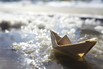 Paper boat in the water on the street. The concept of early spring. Melting snow and an origami...