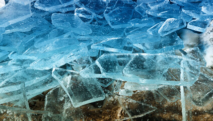 background of pieces of crystal clear blue ice on the river bank