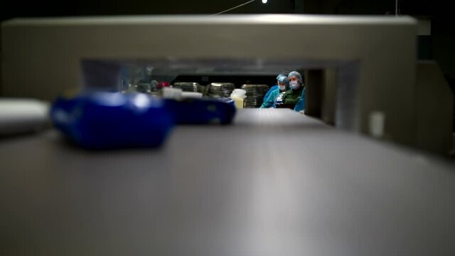 Big blue packs of macaronis moving on the conveyor to the packers workers. Work scene of modern food industry