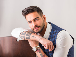 Trendy young man in studio shot wearing elegant vest and white shirt, looking at camera