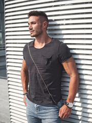 One handsome young man in urban setting in European city, wearing jeans and black t-shirt