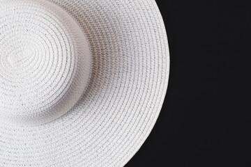 Fototapeta na wymiar A large white beach lady's hat on a black background. The concept of vacation, vacation, travel, sales, black Friday.