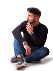 Full body shot of handsome young man with shirt and jeans sitting on the floor, isolated on white
