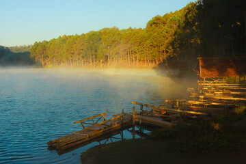 A lake and a small pier surrounded by a forest on a hilltop