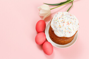 Easter cake on a plate, eggs and tulip flower with pink background.