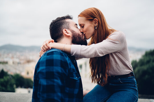 Side view of calm couple in love kissing and hug during together travel vacations enjoying warm feelings, beautiful Caucasian people in casual clothing flirting during romantic date in city