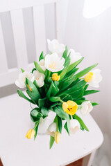 Yellow and white tulip bouquet on white chair