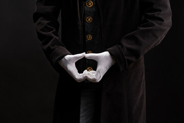 Hand gestures. magician clasped his hands together. Showman or magician illusionist in white gloves on a black background.