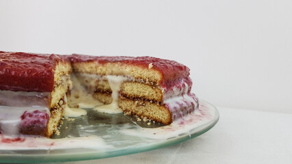 the red cake and the piece cut off from it lie on a white plate on a white background