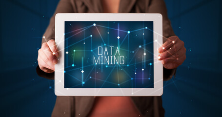 Young business person working on tablet and shows the digital sign: DATA MINING