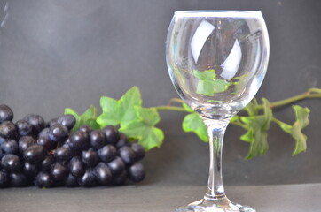 bottle of red wine wineglasses with grapes and corks on dark background with copy space