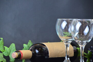 bottle of red wine wineglasses with grapes and corks on dark background with copy space