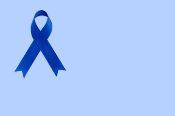 Blue ribbon on blue background with copy space. Colorectal Cancer Awareness. Colon cancer of older person. World diabetes day.