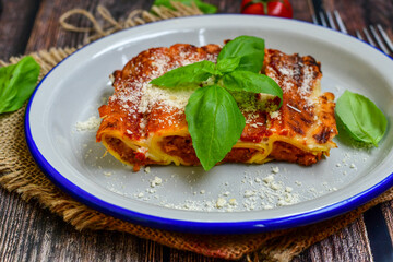 Cannelloni bolognese and parmesan cheese  on a wooden rustic  background.Home made italian meal
