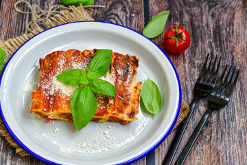 Cannelloni bolognese and parmesan cheese  on a wooden rustic  background.Home made italian meal
