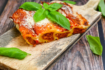 Cannelloni bolognese and parmesan cheese  on a wooden rustic  background.Home made italian meal
