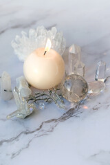 Fototapeta na wymiar Clear quarz minerals and candle on marble background. Crystal Ritual, wiccan Witchcraft, life balance concept.