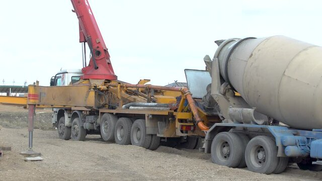 Concrete mixer truck delivers unloads loads mortar to mobile pump. Construction machinery works on site or building object