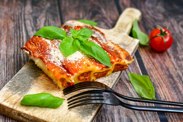 Cannelloni bolognese and parmesan cheese  on a wooden rustic  background.Home made italian meal