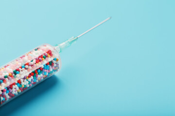 Syringe with colorful balloons on a blue background with free space.