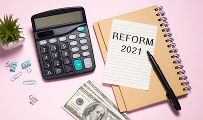 The text Reform 2021 on office desk with calculator, markers, glasses and financial charts.