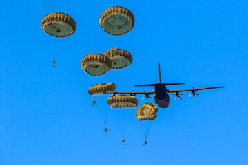 Military parachutist paratroopers parachute jumping out of a air force planes on a clear blue sky...