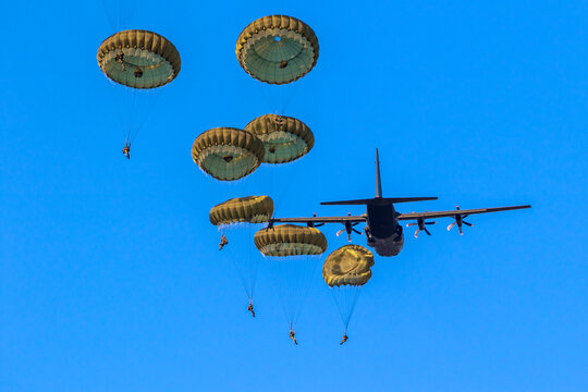 Military Parachutist Paratroopers Parachute Jumping Out Of A Air Force Planes On A Clear Blue Sky Day.