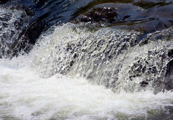 Close up of water spilling over rocks.