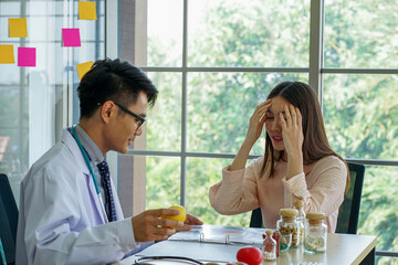 Asian medical doctor wearing stethoscope advising young beautiful patient about healthy diet fruits and virus protection